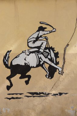 Graffiti of rodeo, man riding horse. Old Wall, Argentina
