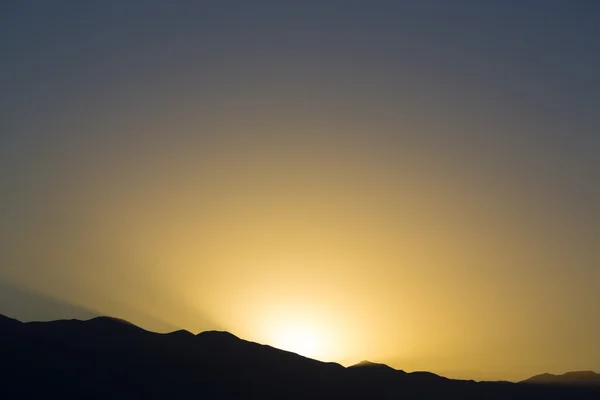 Raios de pôr do sol dramáticos atrás da silhueta de de montanha — Fotografia de Stock