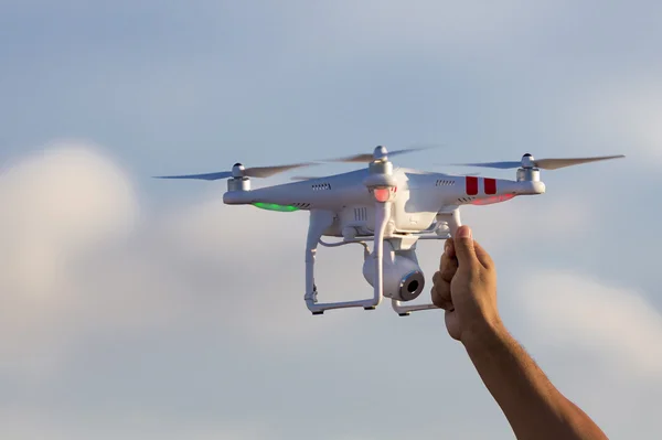 Vit drone svävar i en ljus blå himmel med hand redo att katt — Stockfoto