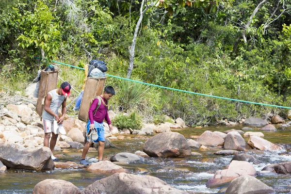 Indian native guides crossing river with traditional backpacks — 图库照片