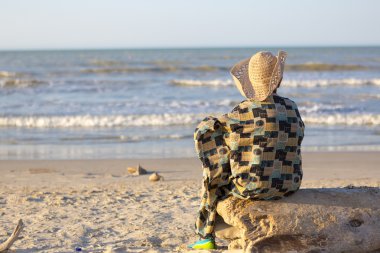 Adam oturmuş ve Kolombiya okyanusa bakarak şapka ile