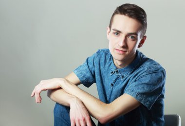 sandalyede oturan tişörtlü adam