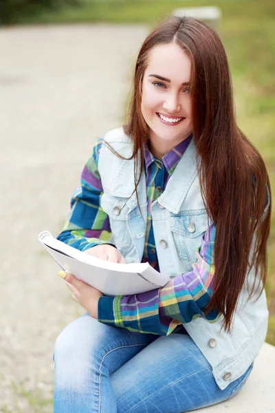 Kitap ile bankta oturan kız — Stok fotoğraf