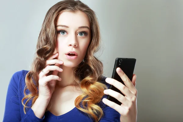 Mujer sorprendida mira el teléfono —  Fotos de Stock