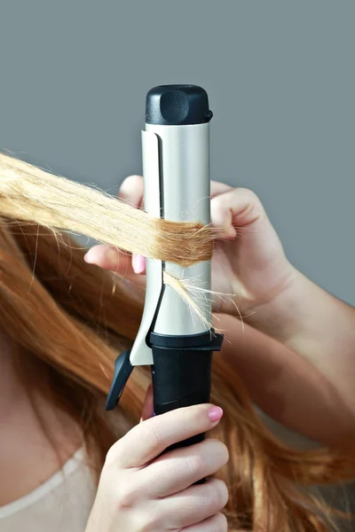 Woman using curling iron on her hair — Stock Photo, Image