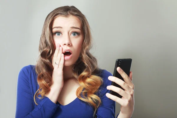 Vrouw verbijsterd op iets op haar mobiele telefoon — Stockfoto