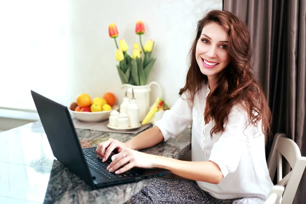 Mulher em casa trabalhando em um laptop — Fotografia de Stock