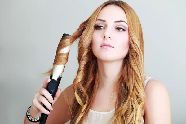 Woman curls her hair — Stock Photo, Image