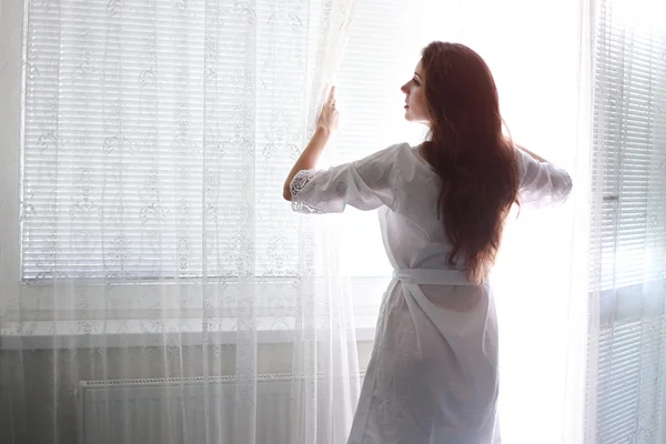 Frau steht am Fenster — Stockfoto