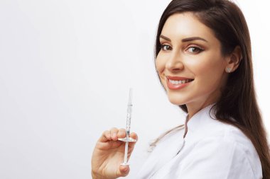 Güzel bayan doktor ya da hemşire elinde şırıngayla gülümsüyor.