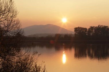 Akşamları buharla kaplanmış sakin bir gölle dramatik dağ manzarası ve karanlık kozalaklı bir orman ve dağların silueti gölün yüzeyine yansıyor.