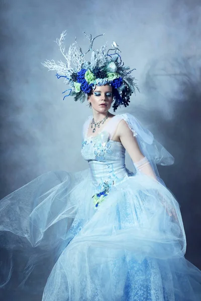 青いドレスと花冠を身に着けているファンタジーキャラクターのような美しい女性のドレッシングの屋内肖像画 — ストック写真