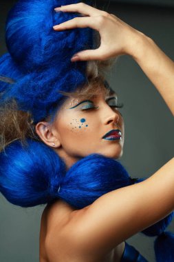 Yaratıcı makyajlı ve mavi saçlı kadın modelin yaratıcı portresi.