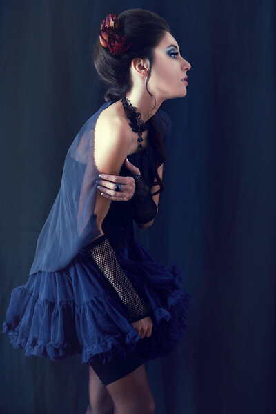 Beautiful fashion vampire victorian style woman posing over dark background