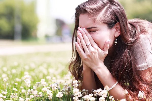 Girl sneezing in a field of flowers — Stock Photo, Image