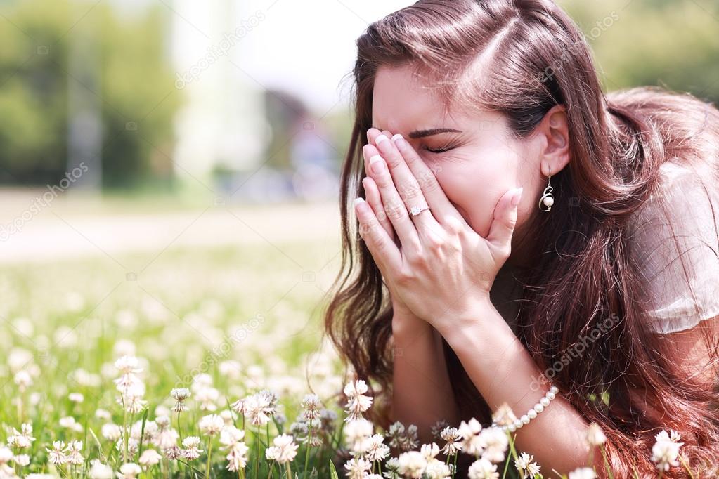 girl sneezing in a field of flowers