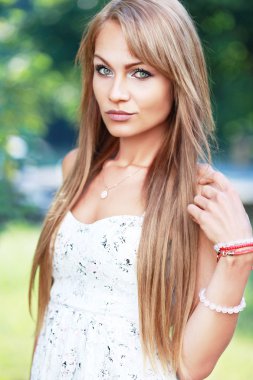 Park yerinde poz veren genç kadın.