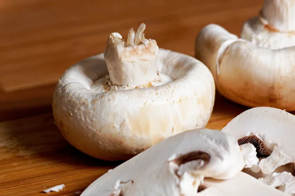 Cogumelos brancos inteiros e fatiados em tábua de madeira — Fotografia de Stock