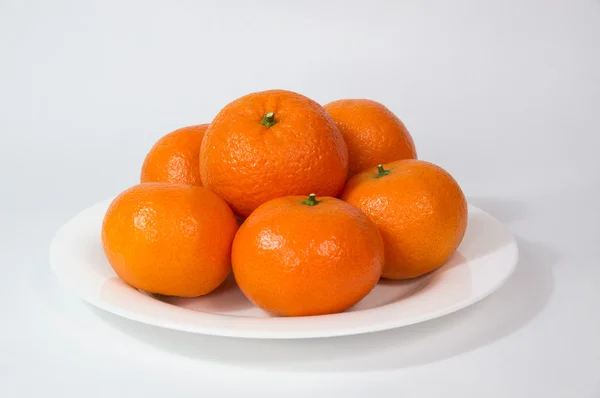 Grandes mandarinas doradas sobre plato blanco — Foto de Stock
