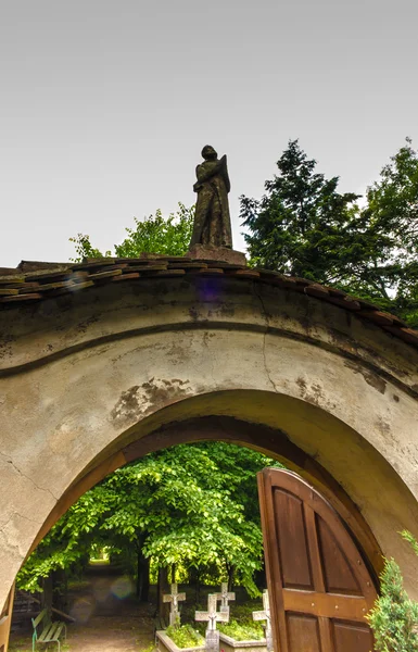 Фигура молящегося монаха на воротах, ведущих к кладбищу, — стоковое фото