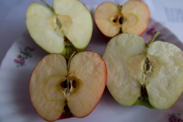Halves of two sliced apples. One apple has grains and the other has been modified so that there are no grains.