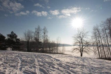 Güneşli bir kış gününde karla kaplı bir gölün üzerindeki buz kabuğu.