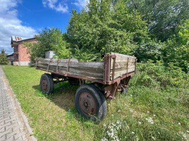 Eski, harap olmuş bir traktör römorku yolun kenarına park etmiş, çimlerin arasına, çalıların arasına..