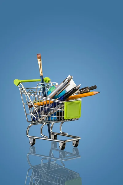 Trolley with school equipment on blue background — Stock Photo, Image