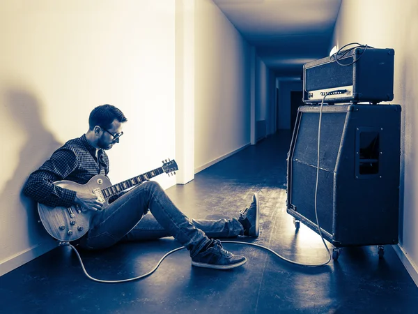 Tocando su guitarra eléctrica en el pasillo — Foto de Stock