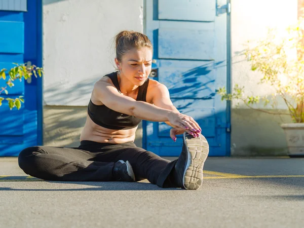 Young woman stretching her legs outdoors — Stock Photo, Image