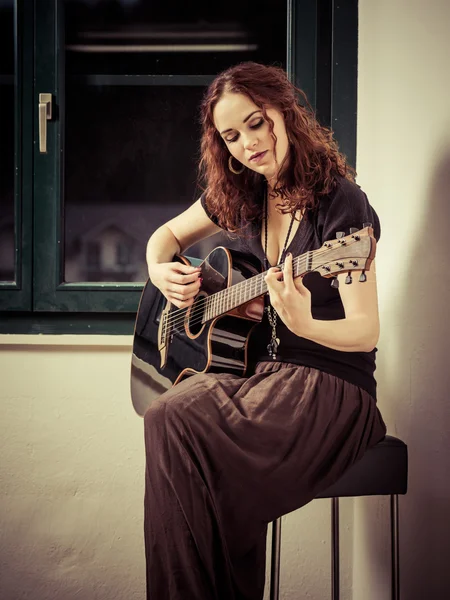 Giovane donna che suona la chitarra alla finestra — Foto Stock