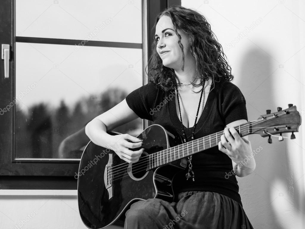 Happy woman playing acoustic guitar