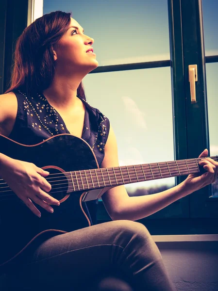 Piękna kobieta gra na gitarze przez okno — Zdjęcie stockowe