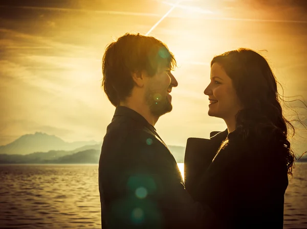 Pareja de pie junto al lago a la luz del sol — Foto de Stock