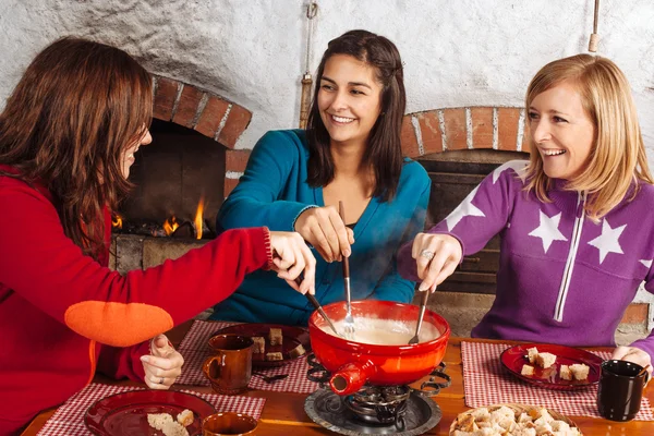 Freunde beim Fondue-Essen Stockbild