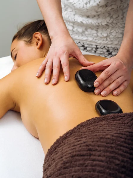 Massage therapist placing the hot stones — Stock Photo, Image