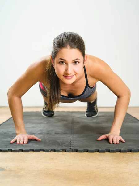 Junge Frau macht Liegestütze — Stockfoto