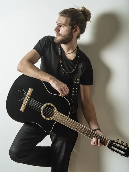 Pohledný mladý muž, držící akustická kytara — Stock fotografie