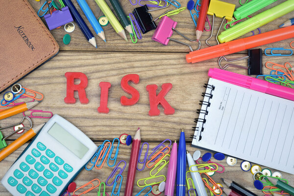 Рискованное слово и офисные инструменты на деревянном столе
