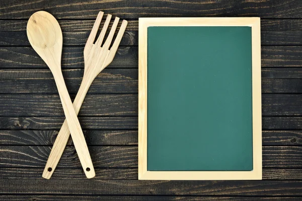 Utensilios de cocina y tablero verde en la mesa — Foto de Stock