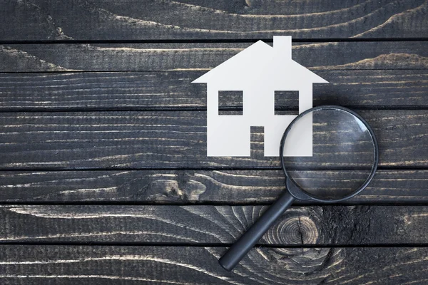 Magnifying glass and paper house on table — Stock Photo, Image