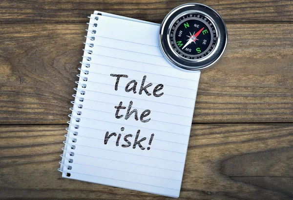 De tekst van de risico's en kompas overneemt met houten tafel — Stockfoto