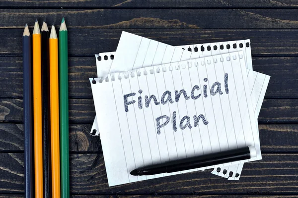 Texto del plan financiero sobre bloc de notas y herramientas de oficina — Foto de Stock