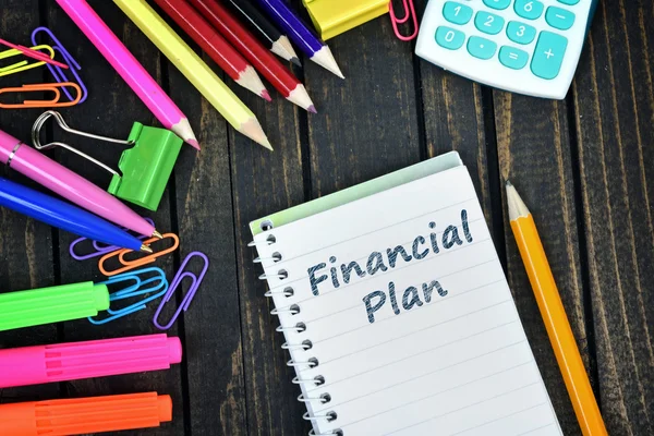 Texto del plan financiero sobre bloc de notas y herramientas de oficina —  Fotos de Stock