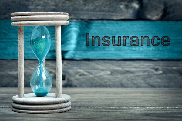 Texto del seguro y reloj de arena en la mesa — Foto de Stock