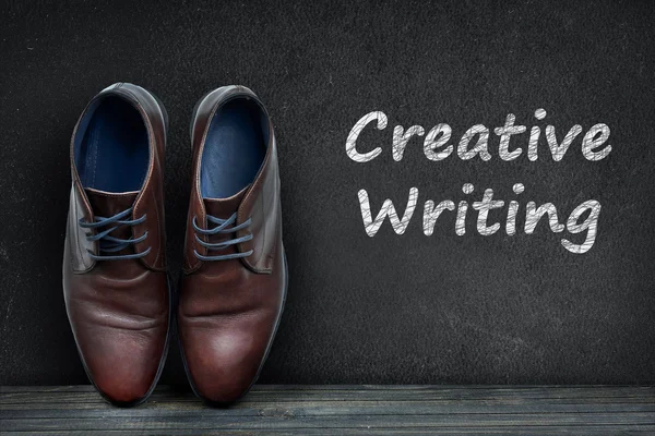 Creative Writing text on black board and business shoes