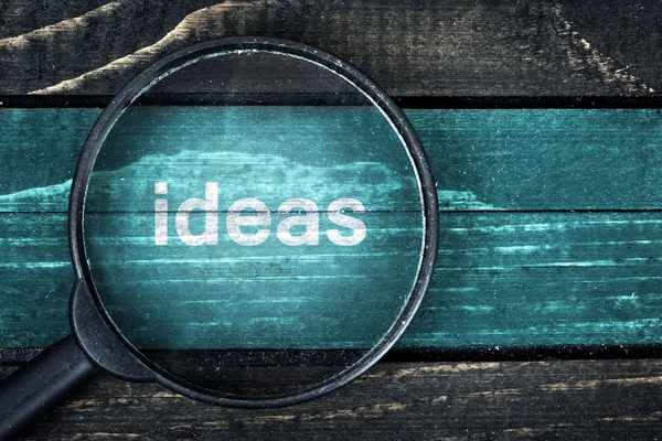 Ideas text painted and magnifying glass on table — Stock Photo, Image