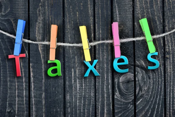 Impostos palavra pendurada em clipes — Fotografia de Stock