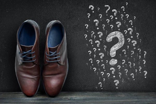 Question marks text on black board and business shoes — Stock Photo, Image