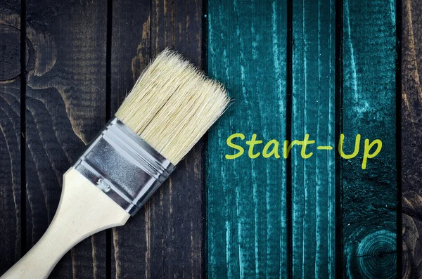 Start-up bericht en penseel op muur — Stockfoto